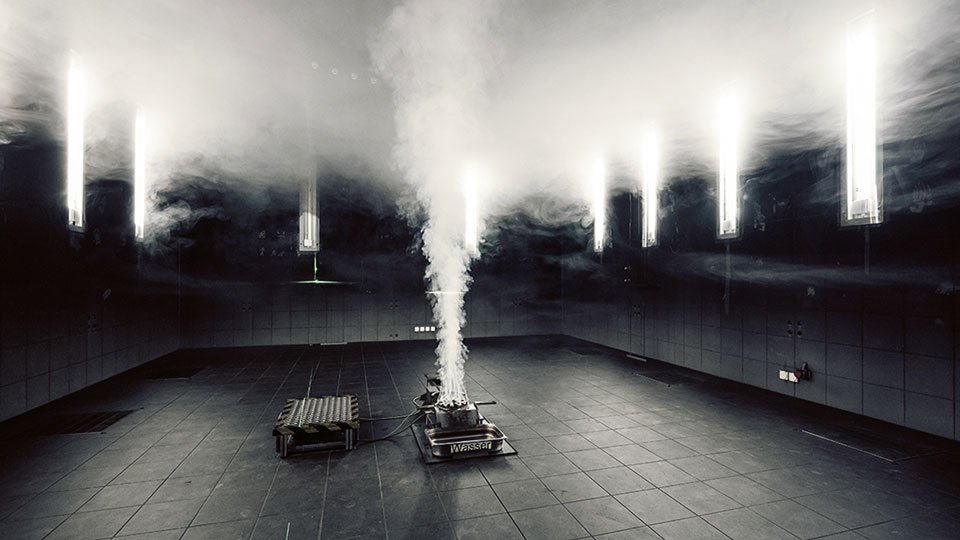 Ein schwarzer Raum in dem eine Rauchmaschine steht und einen Brand simuliert.