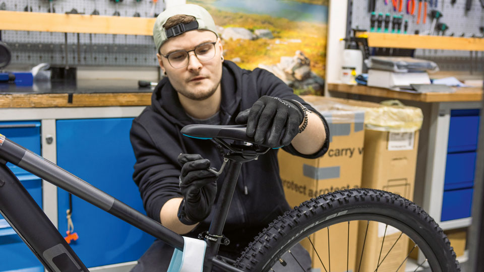 Auf dem Bild ist ein junger Mann der ein Fahrrad repariert